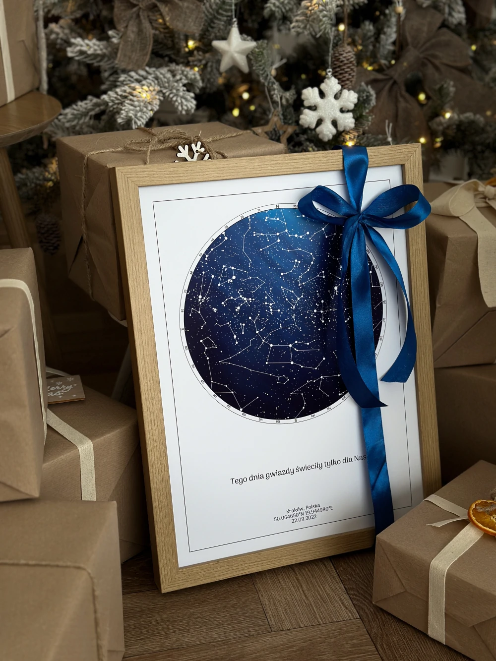 Romantyczny prezent dla chłopaka na święta przewiązany błękitną wstążką, stojący pod choinką wśród innych paczek.