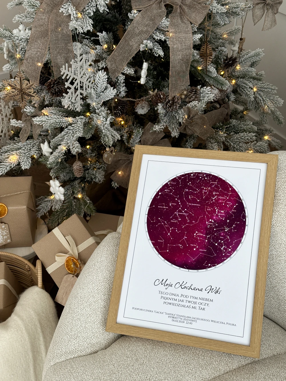 Romantyczny prezent na święta dla żony lub dziewczyny w drewnianej ramie, stojący bezpośrednio przy oświetlonej choince.
